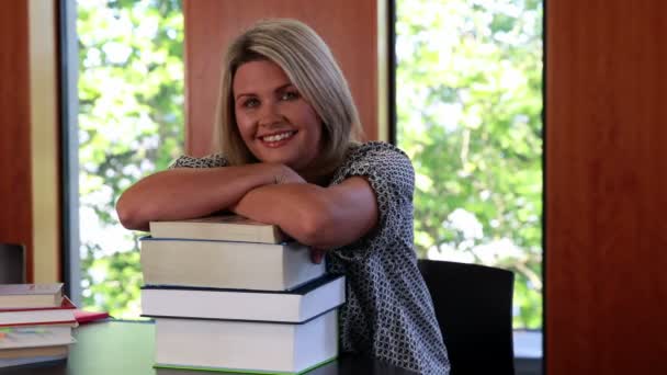 Mature student leaning on pile of books — Stock Video