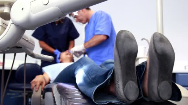 O paciente contorce-se na cadeira do dentista — Vídeo de Stock