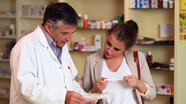 Farmacéutica explicando prueba de embarazo a mujer joven — Vídeo de stock