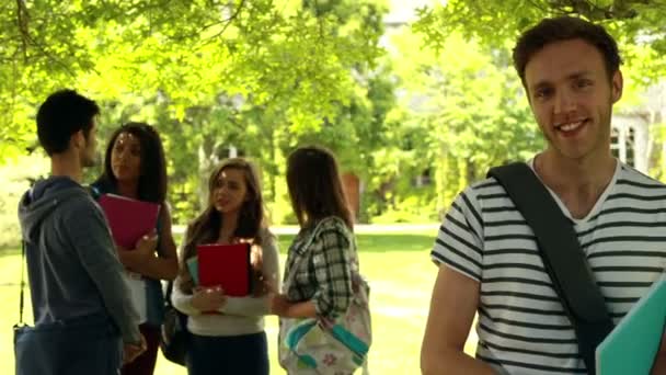 Student posing and classmates speaking behind him — Stock Video