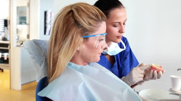 Dentista hablando con paciente mostrando modelo de boca — Vídeo de stock