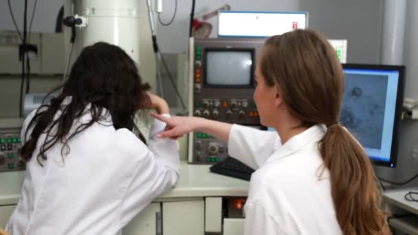 Estudiantes de ciencias trabajando juntos con microscopio — Vídeo de stock