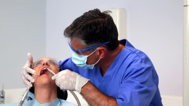 Стоматолог с помощью всасывающего шланга на пациента — стоковое видео