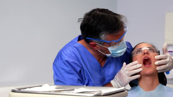 Стоматолог, осматривающий зубы пациента — стоковое видео