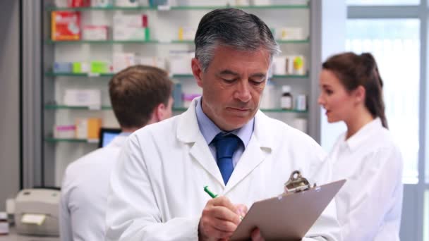 Senior pharmacist writing on clipboard — Stock Video