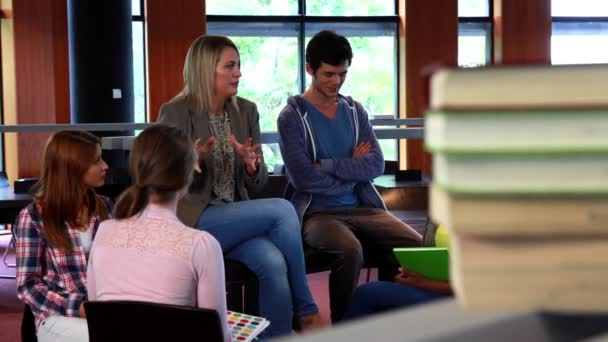 Студенты и преподаватели обсуждают в библиотеке — стоковое видео