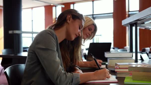 Estudante com colegas escrevendo notas na mesa — Vídeo de Stock