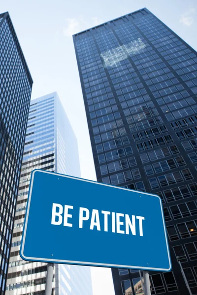 Be patient against low angle view of skyscrapers — Stock Photo, Image