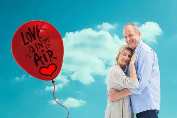 Imagen compuesta de feliz pareja madura abrazando y sonriendo — Foto de Stock