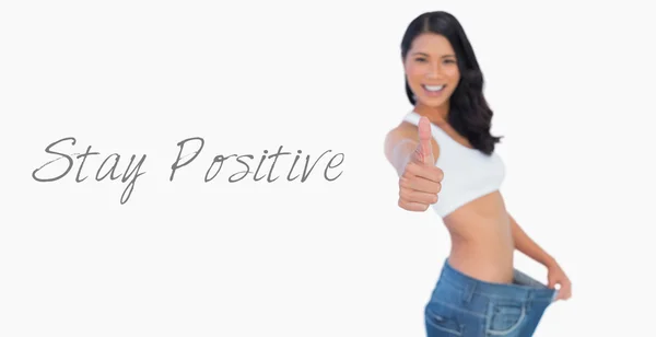 Victorious woman holding her too big pants thumbs up — Stock Photo, Image