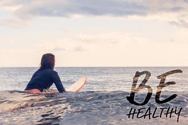 Imagem composta da visão traseira de uma mulher sentada na prancha de surf em — Fotografia de Stock