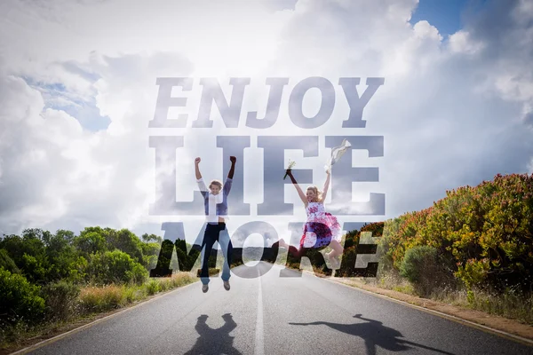 Composite image of excited couple jumping on the road — Stock Photo, Image