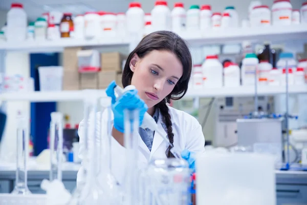 Geconcentreerde vrouwelijke wetenschapper met behulp van een precisiepipet — Stockfoto