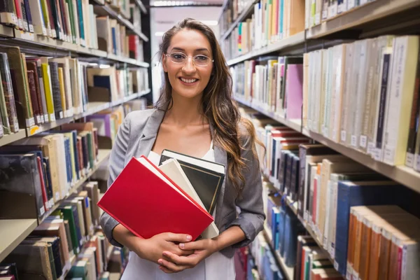 Mooie student plukken uit een boek in de bibliotheek — Stockfoto