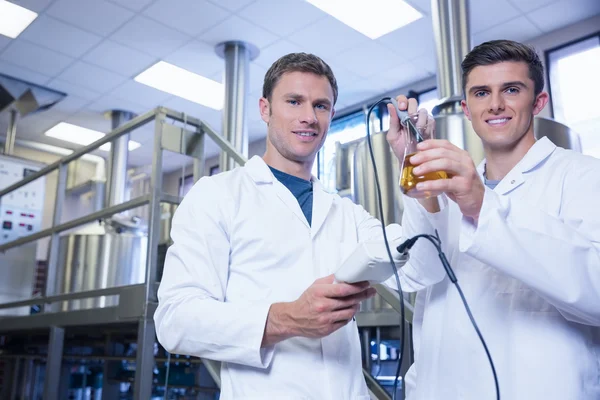 Hombres probando el producto y sonriendo a la cámara — Foto de Stock