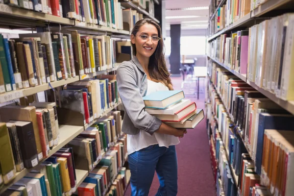 Pretty student smiling at camera in library — Stock Photo, Image