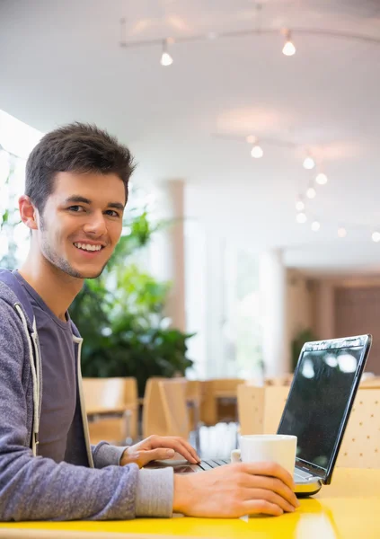 Ung student med sin laptop i café — Stockfoto