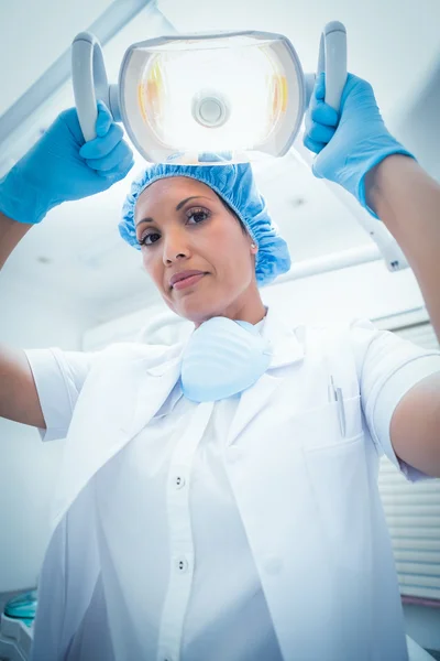 Dentista femenina grave ajustando la luz — Foto de Stock