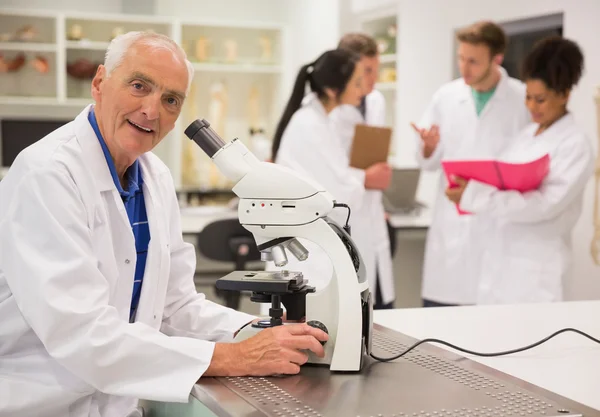 Professeur de médecine souriant travaillant au microscope — Photo