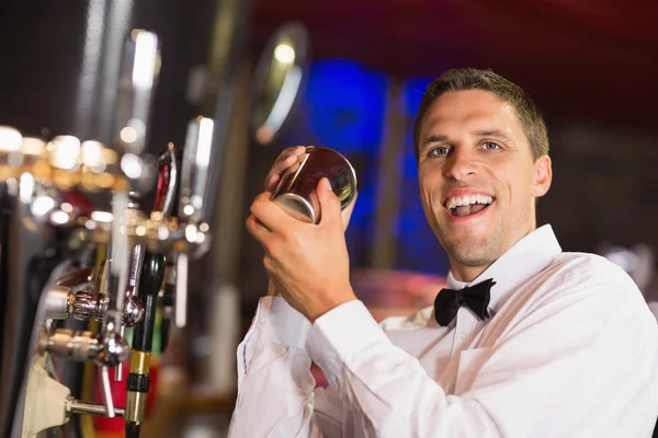 Bonito barman sorrindo para a câmera fazendo um coquetel — Fotografia de Stock