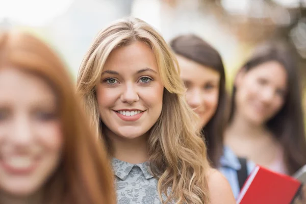 Estudantes felizes sorrindo para a câmera em uma fileira — Fotografia de Stock