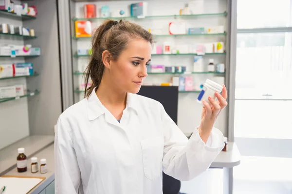 Junior pharmacist looking at medicine — Stock Photo, Image