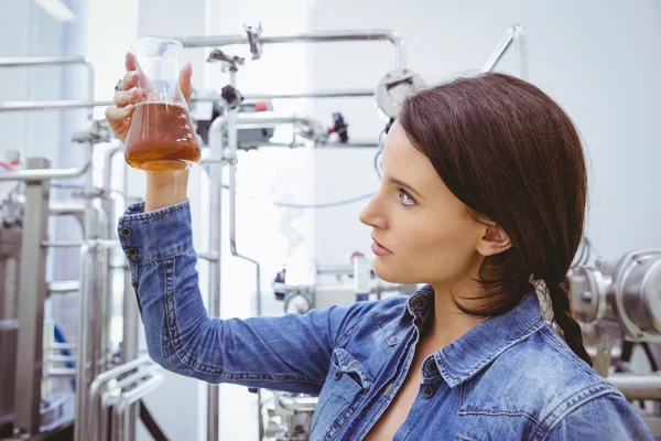 Bruna elegante in giacca di jeans guardando becher di birra — Foto Stock