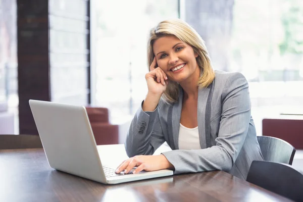 Білявка бізнес-леді посміхається за допомогою ноутбука — стокове фото