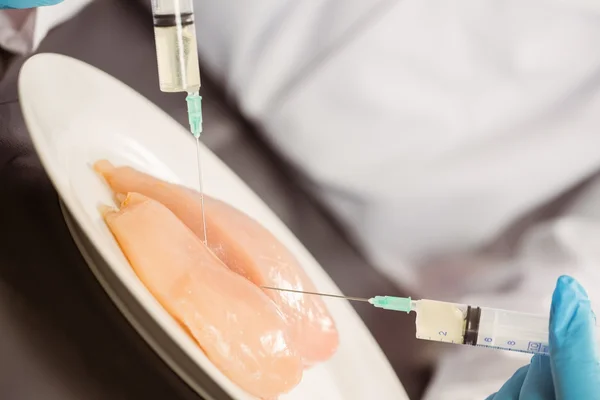 Scientifique alimentaire injectant du poulet cru — Photo