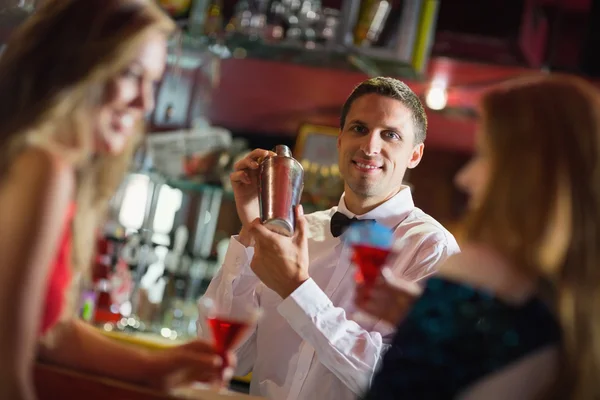 Bonito barman sorrindo para a câmera fazendo um coquetel — Fotografia de Stock