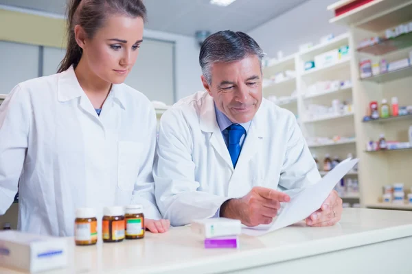 Pharmacist showing a prescription to his trainee — Stock Photo, Image