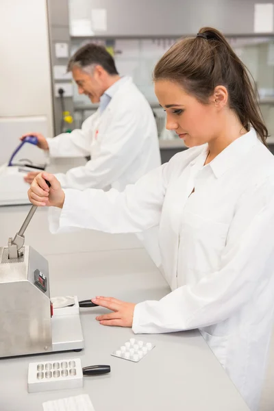 Pharmacist using press to make pills — Stock Photo, Image