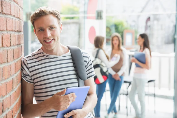 Handsome student smiling and holding tablet — Stock Photo, Image