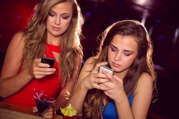 Amigos bonitos mirando teléfonos inteligentes — Foto de Stock