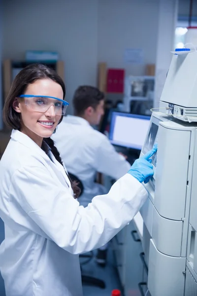 Sorridente giovane chimico utilizzando la macchina — Foto Stock