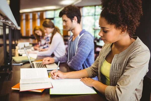 Studenti concentrati seduti in fila a scrivere — Foto Stock