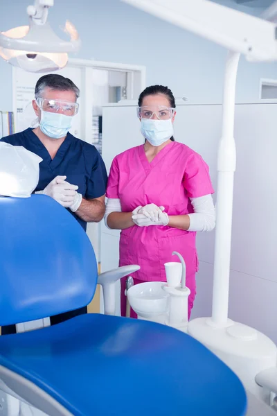 Dentista y asistente en máscara quirúrgica y gafas protectoras — Foto de Stock