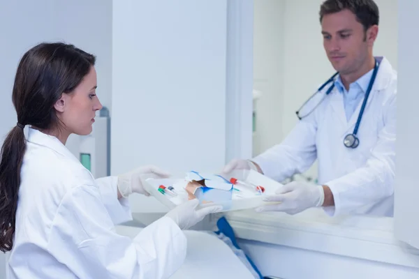 Doctor giving tray with blood sample to his colleague — Stock Photo, Image