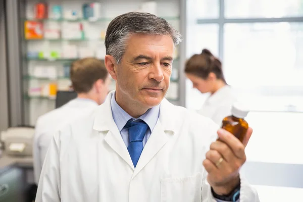 Senior pharmacist looking at medicine — Stock Photo, Image
