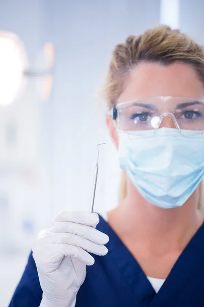 Dentist in mask holding dental explorer — Stock Photo, Image