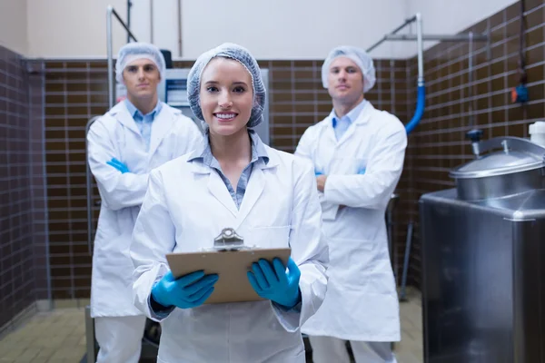 Girl holding a clipboard with these colleagues behind her — Stock Photo, Image