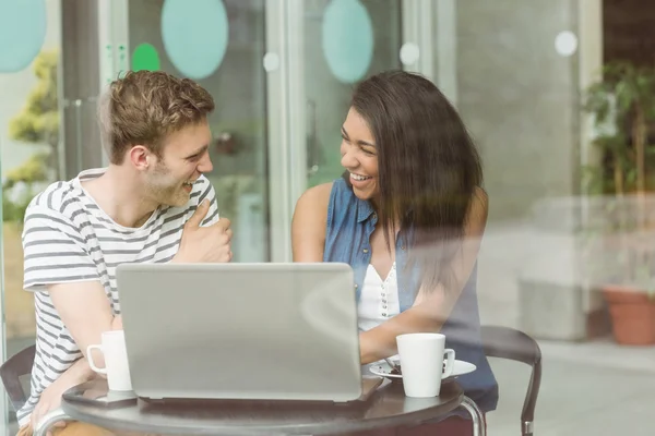 Amigos sonrientes con pastel de chocolate usando computadora portátil — Foto de Stock