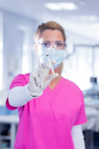 Dentist in surgical mask and scrubs holding syring — Stock Photo, Image