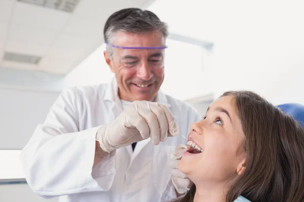 Dentista pediátrico usando fio dental para seu jovem paciente — Fotografia de Stock