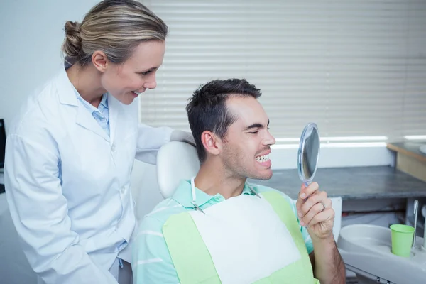 Smiling young man looking at mirror — Stock Photo, Image