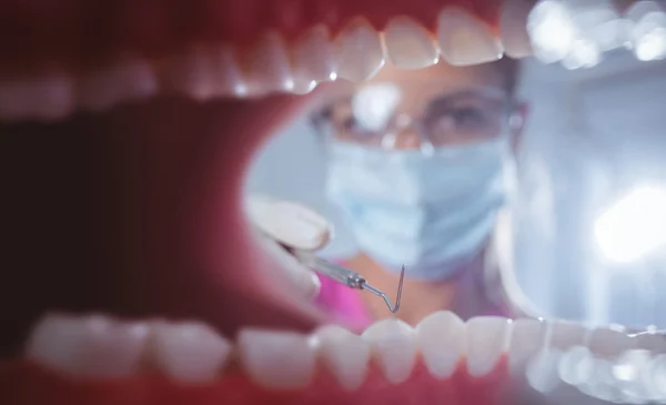 Primer plano de una boca abierta con el dentista detrás — Foto de Stock