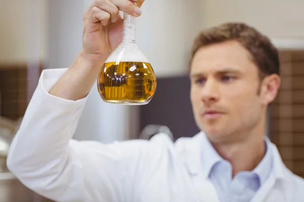 Focused scientist holding beaker with beer — Stock Photo, Image