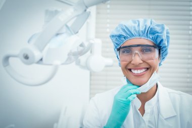 Female dentist wearing surgical cap and safety glasses clipart