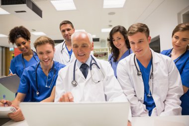 Medical students and professor using laptop clipart