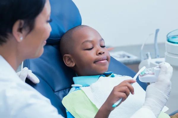 Female dentist teaching boy how to brush teeth — Stock Photo, Image